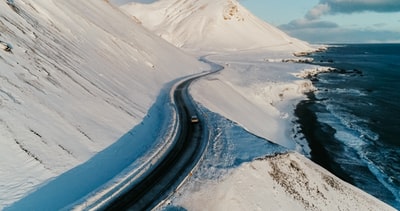 在白昼积雪覆盖的地面之间的黑色沥青路